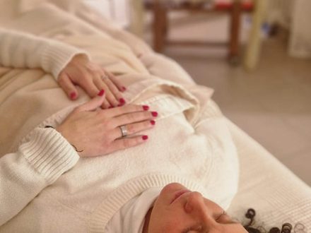 Una persona distesa durante un trattamento Reiki, con le mani della praticante appoggiate sul petto